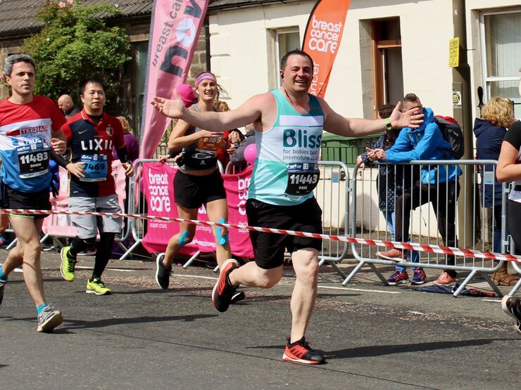 Male running the Edinburgh marathon with arms outstretched wearing a Bliss running vest