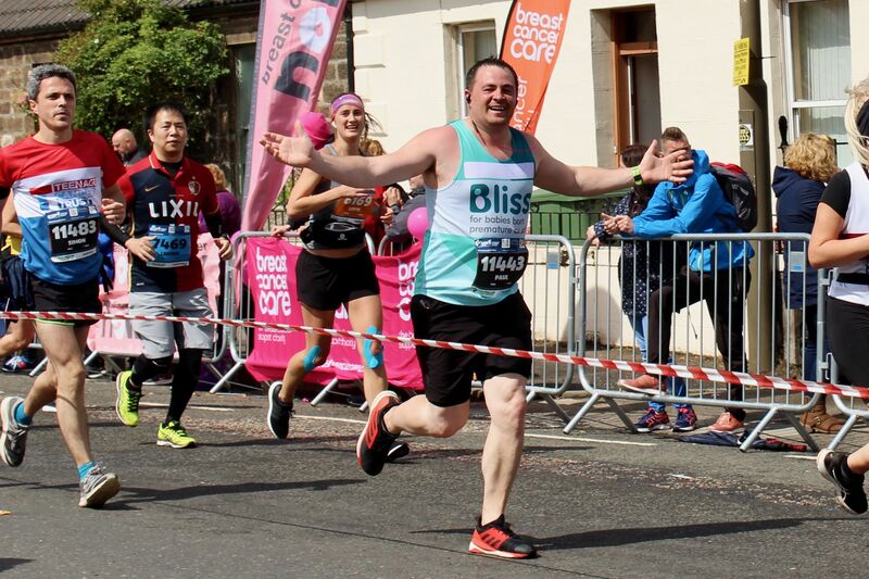 Male running the Edinburgh marathon with arms outstretched wearing a Bliss running vest