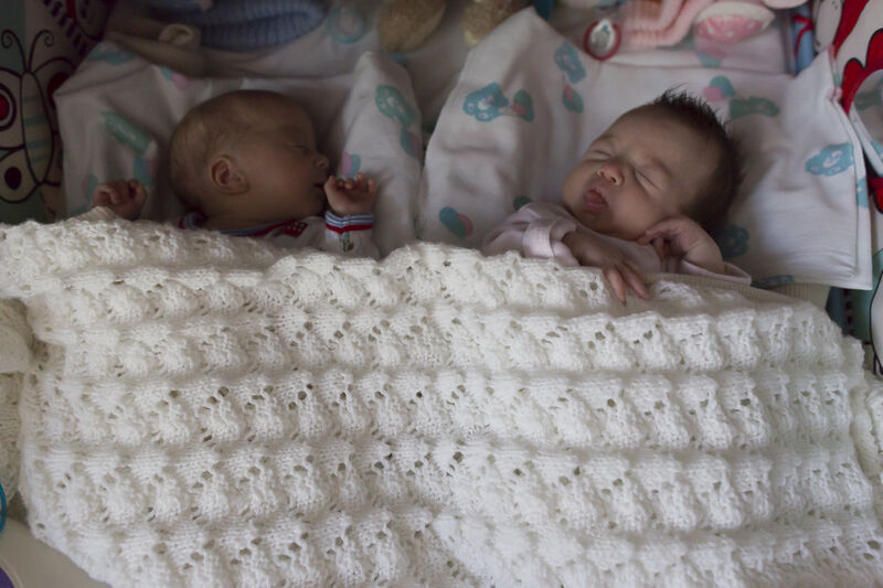Twins sleeping peacefully next to each other underneath a blanket