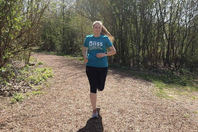 Person running on dirt path wearing a Bliss t-shirt