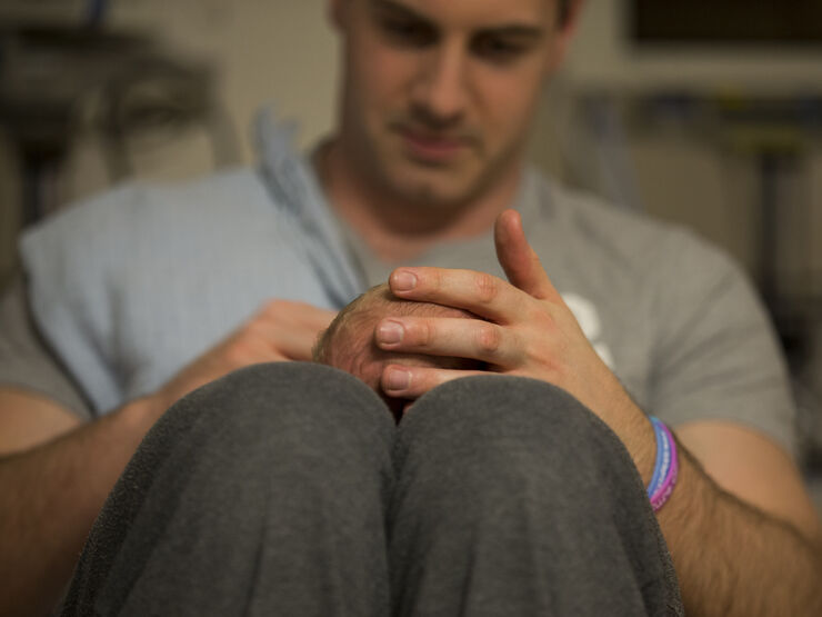 Dad with his baby lying on his lap, holding the baby's head
