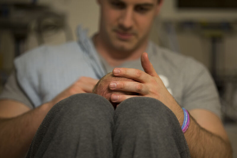 Dad with his baby lying on his lap, holding the baby's head