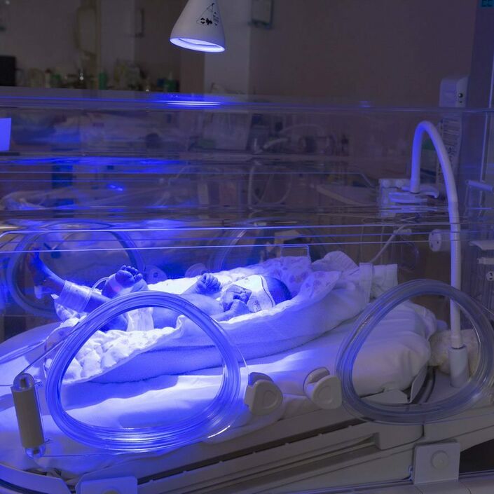 Baby in an incubator undergoing blue light phototherapy