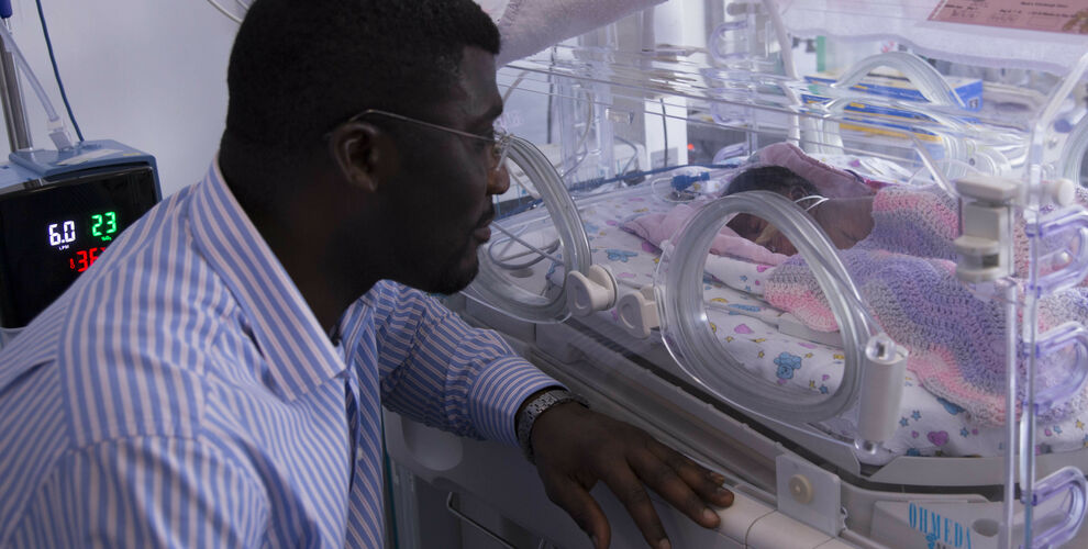 Father looking longingly at his child through an incubator