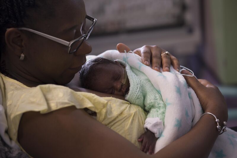 Mum holding her baby wrapped in a blanket on her chest