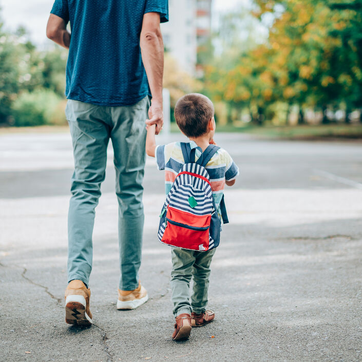 A dad walking with his child and holding their hand