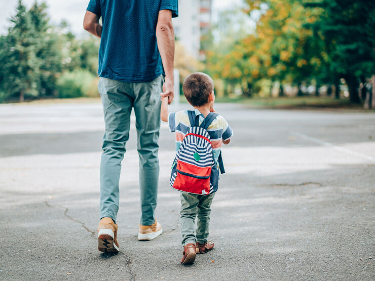 A dad walking with his child and holding their hand