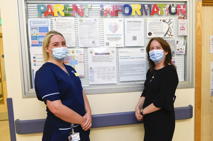 Maree Todd with a member of staff on the neonatal unit, by the parent information board
