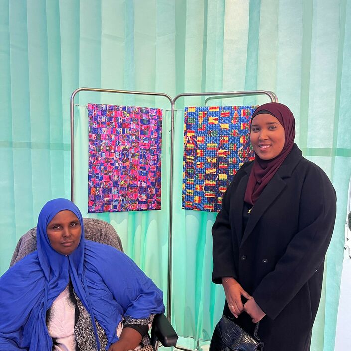 Artist Hafza Yusuf on the right, stood with a fellow community member stood in front of her artwork