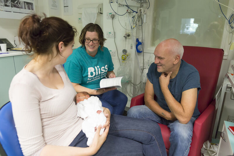 Bliss champion on a unit talking to parents with mum holding the baby