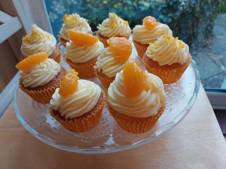orange iced cupcakes on a glass cake stand