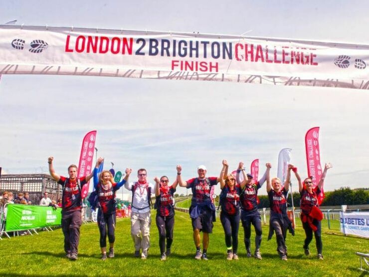 Group of walkers holding hands and crossing the finish line together