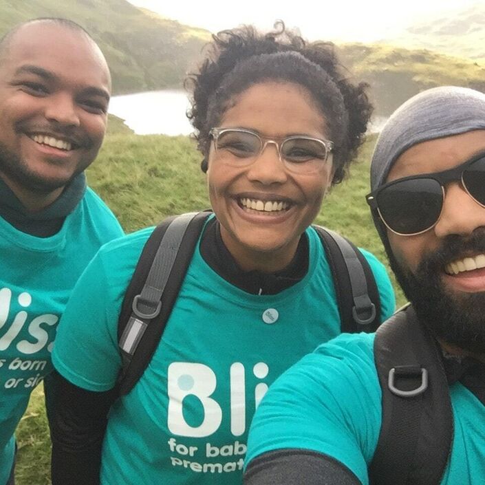 A team of 3 in Bliss t-shirts, smiling, taking a selfie with a lake in the background