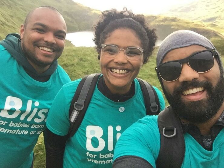 A team of 3 in Bliss t-shirts, smiling, taking a selfie with a lake in the background