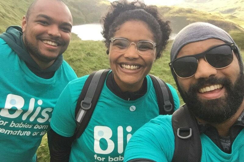 A team of 3 in Bliss t-shirts, smiling, taking a selfie with a lake in the background