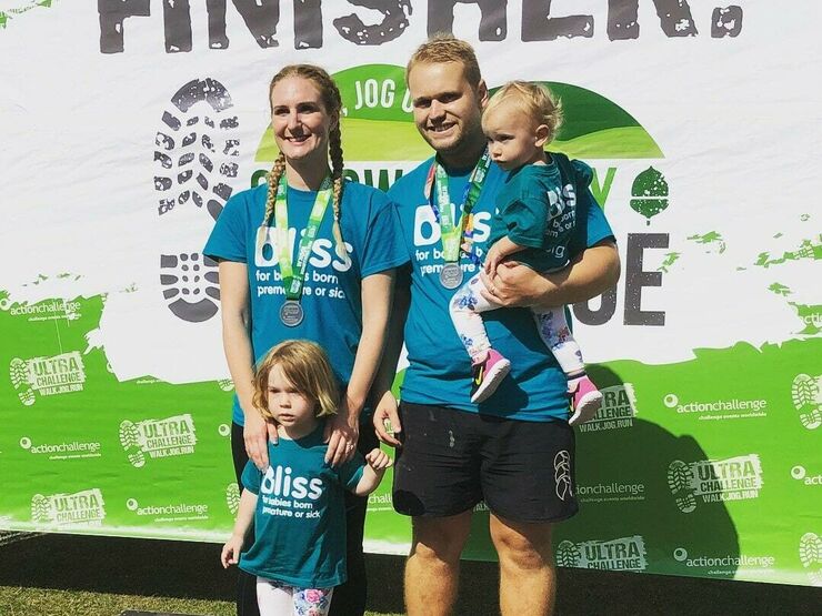 A family of 2 adults and 2 children wearing finisher event medals
