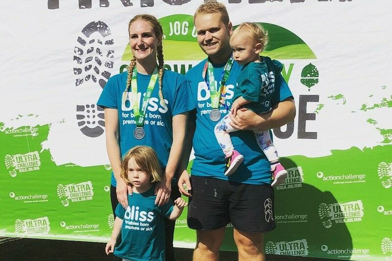 A family of 2 adults and 2 children wearing finisher event medals
