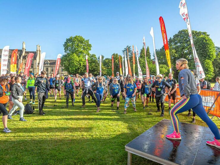 Lots of people at the start area for a walking event, warming up doing stretches