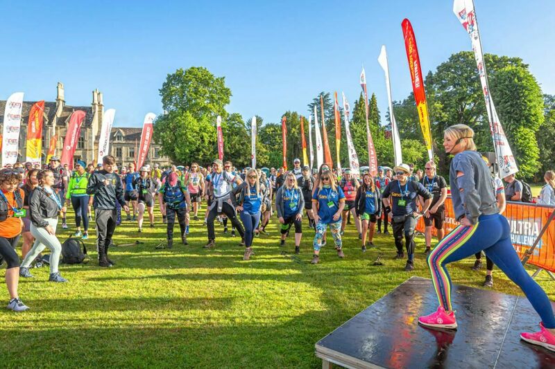 Lots of people at the start area for a walking event, warming up doing stretches