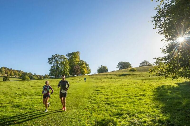 2 walkers coming down a grassy hill with sunshine behind them