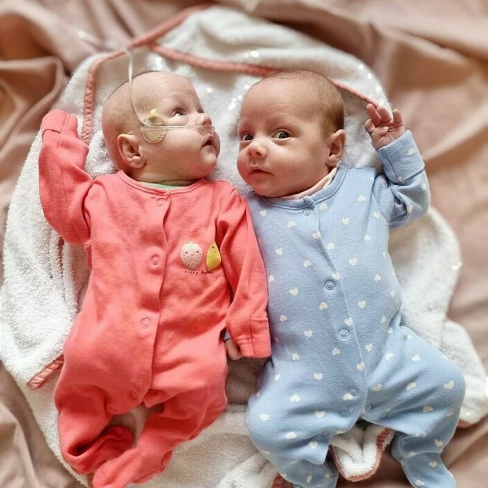 Twin babies wearing pyjamas lying on bed