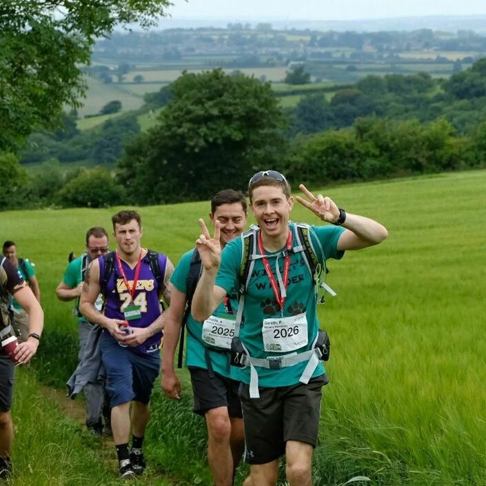 Group of walkers posing to the camera while they walk amongst the countryside