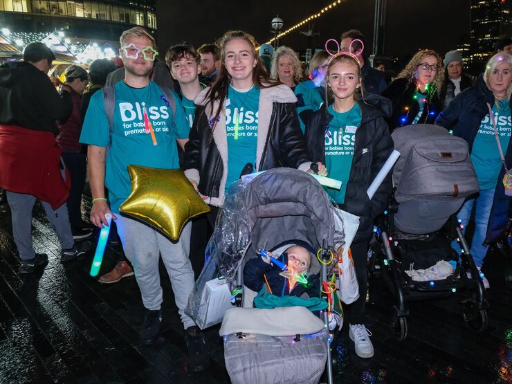 A group of walkers in Bliss t-shirt and lights, there is a small boy in a pram with a gold star balloon