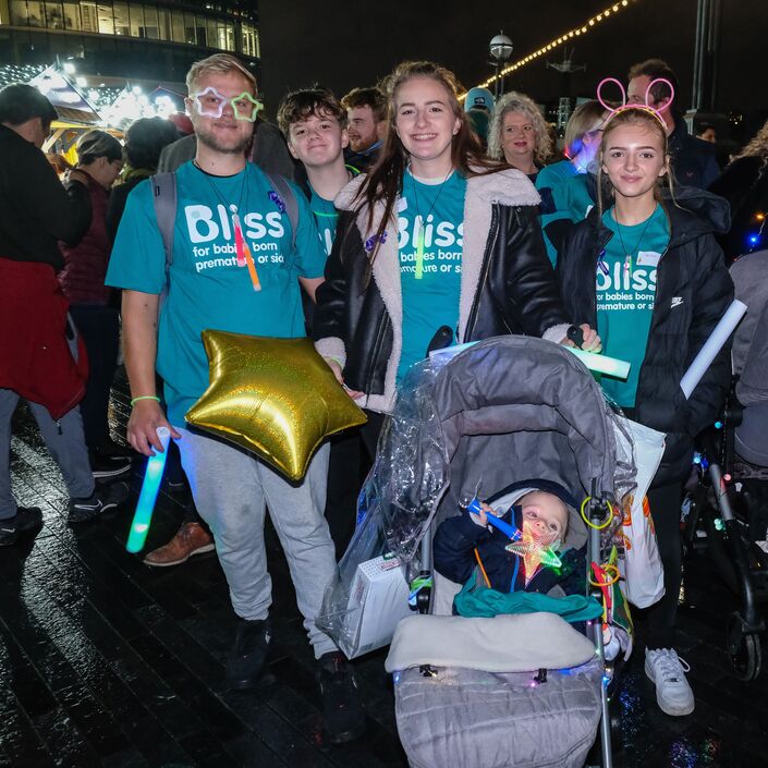 A group of walkers in Bliss t-shirt and lights, there is a small boy in a pram with a gold star balloon