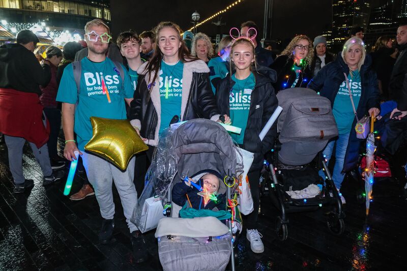 A group of walkers in Bliss t-shirt and lights, there is a small boy in a pram with a gold star balloon