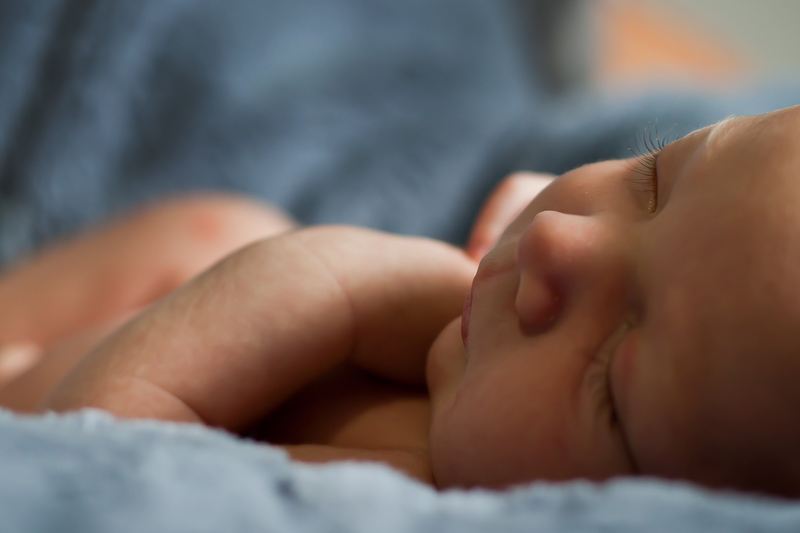 Baby sleeping peacefully with their parent watching over them in the background