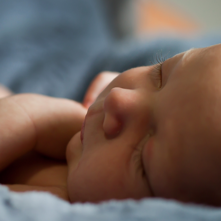 Baby sleeping peacefully with their parent watching over them in the background