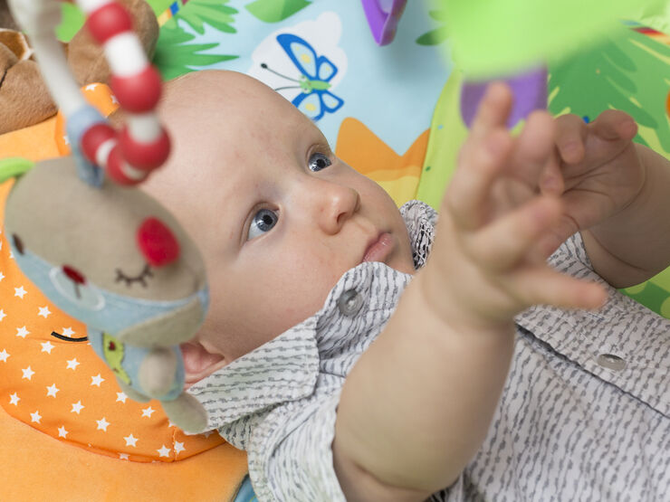 Baby lying on his back reaching up for a toy