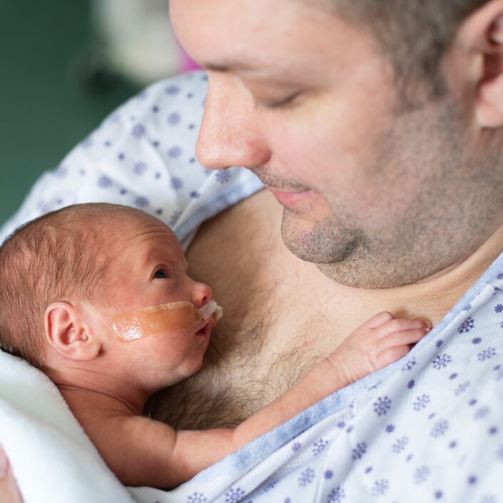 Father taking care of his premature baby doing skin to skin at hospital