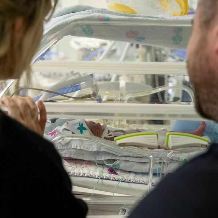 Parents looking at their new born baby in an incubator