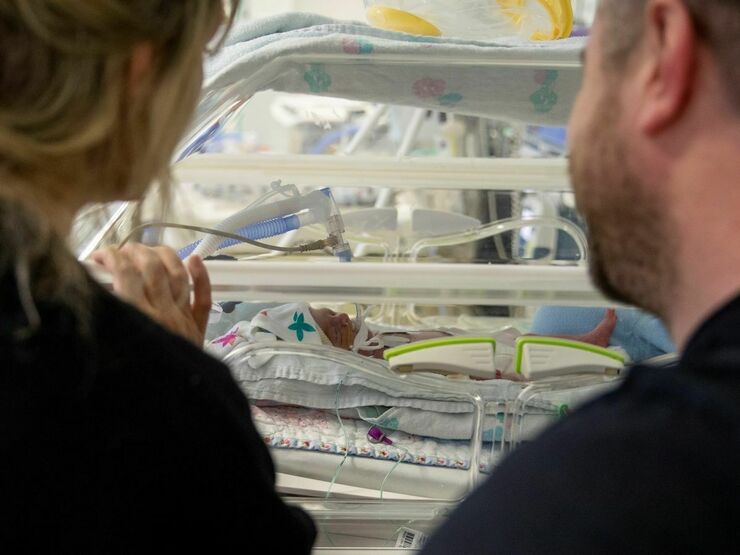 Parents looking at their new born baby in an incubator