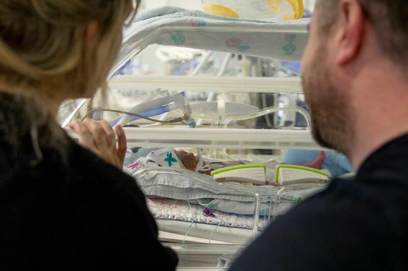 Parents looking at their new born baby in an incubator