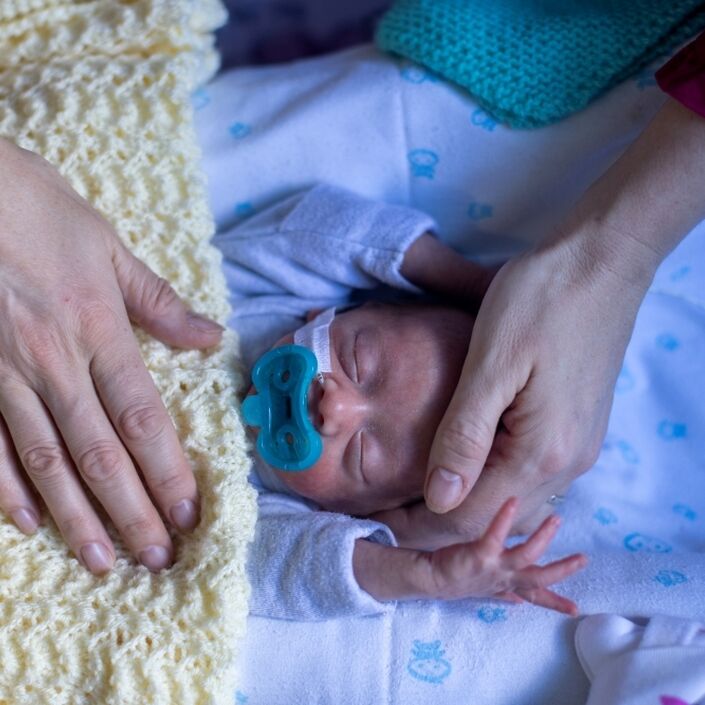 Baby sleeping while parent has their hand on baby's head