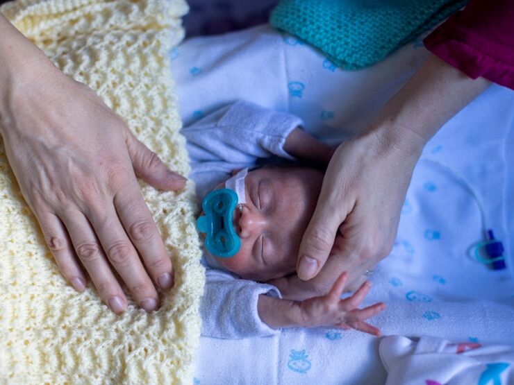 Baby sleeping while parent has their hand on baby's head