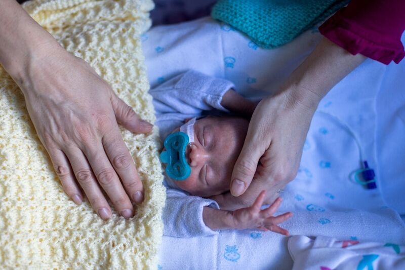 Baby sleeping while parent has their hand on baby's head