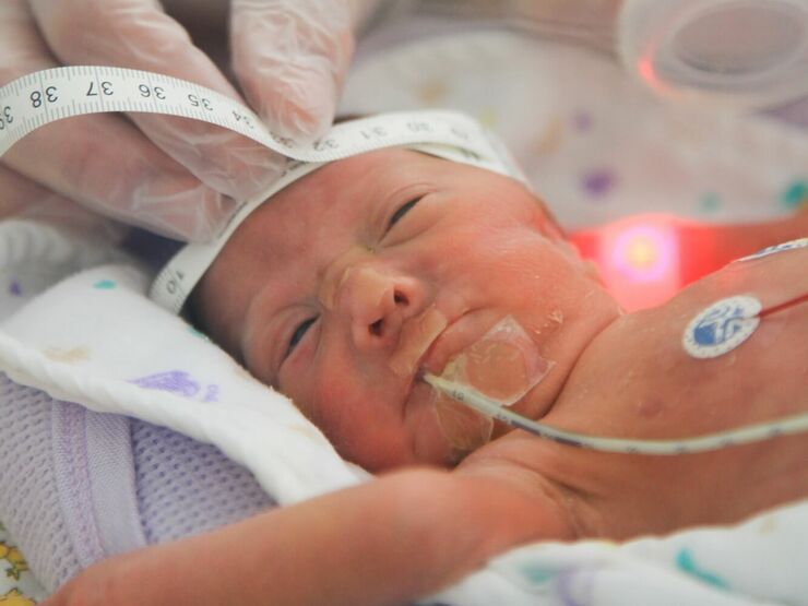 Baby in hospital having its head circumference measured by nurse in gloves