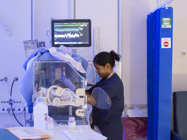 Hospital nurse caring for baby in incubator