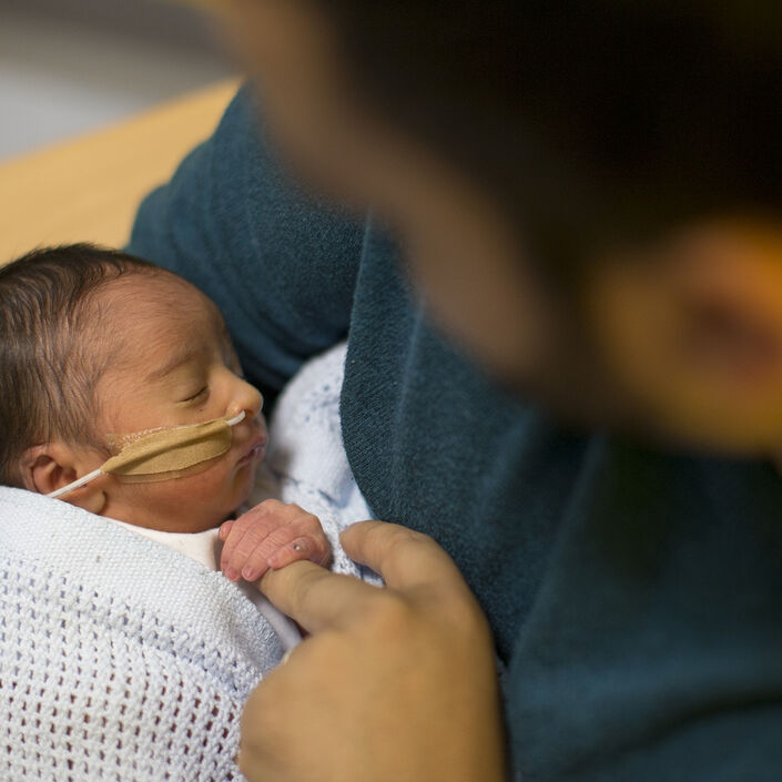 Looking down on dad holding baby with baby holding dad's finger