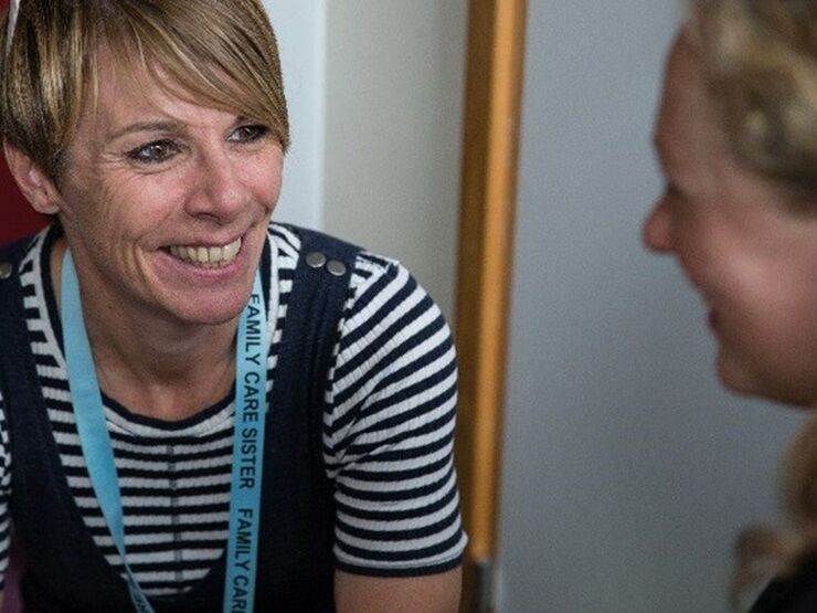 Two professionals sitting down and talking together smiling at each other