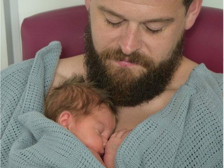 Dad with beard with his baby sleeping peacefully on his chest
