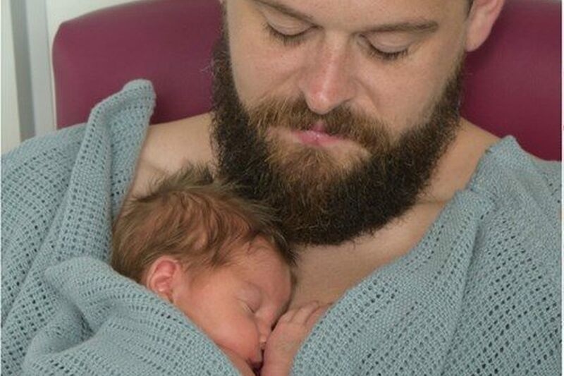 Dad with beard with his baby sleeping peacefully on his chest
