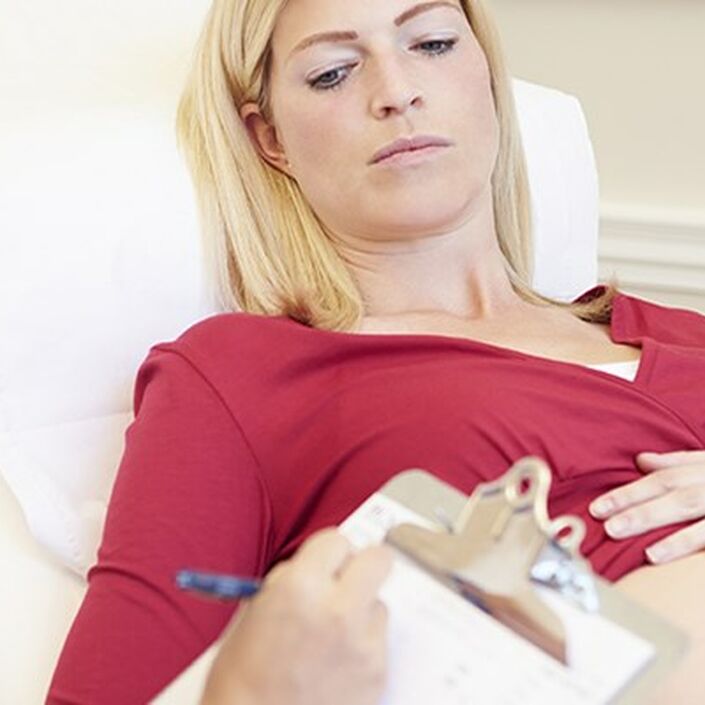 Pregnant woman on hospital bed, with her pregnant belly showing, with midwife writing notes