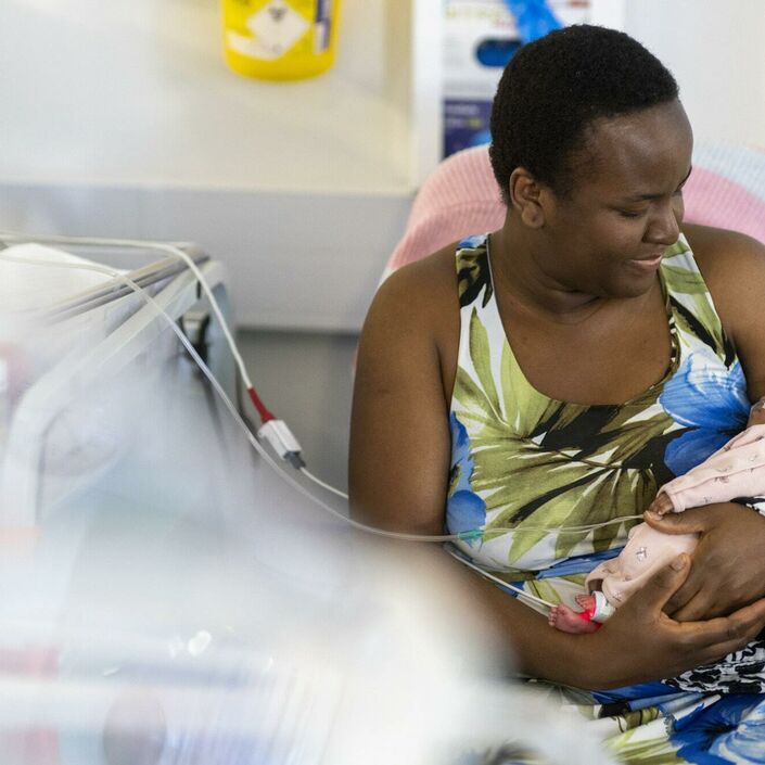 A mum holding her baby in hospital while the baby is attached to some wires