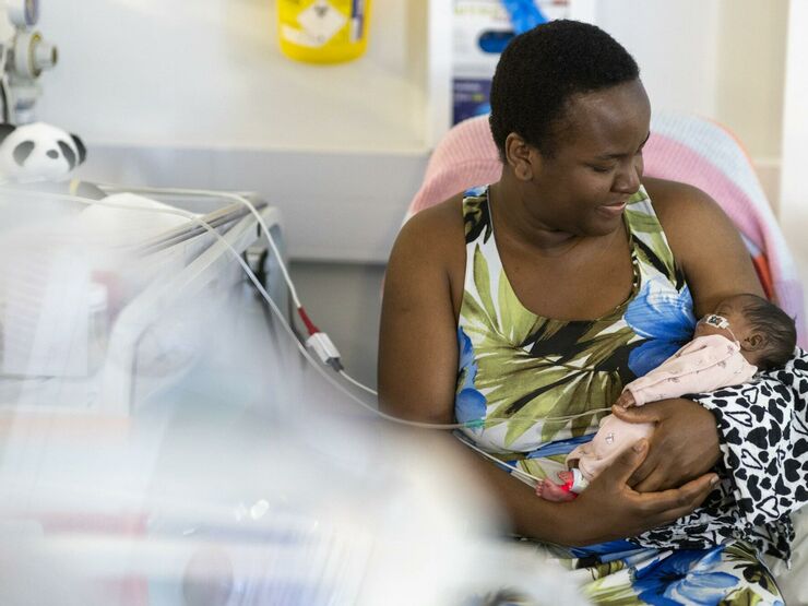 A mum holding her baby in hospital while the baby is attached to some wires