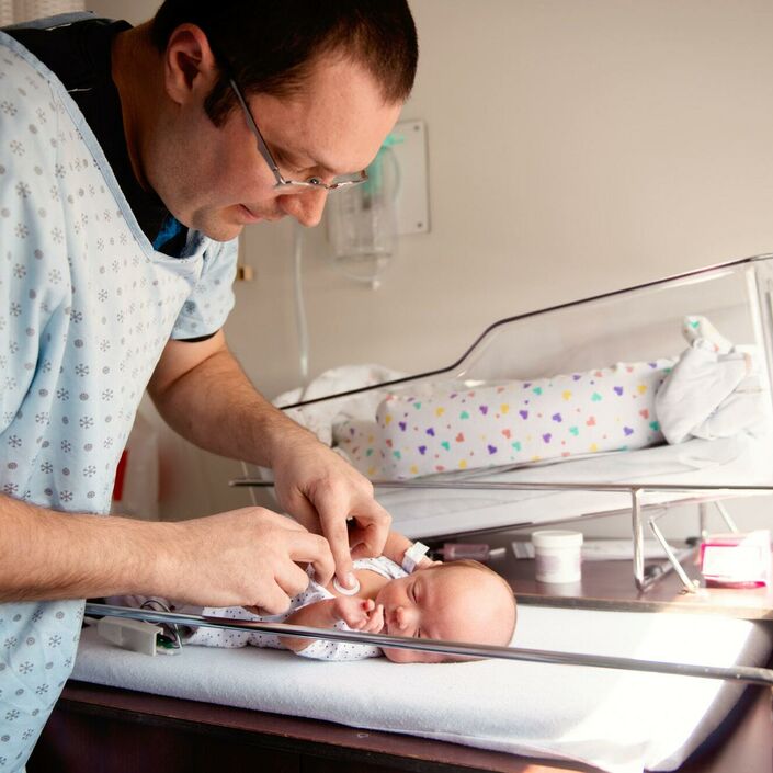 Dad changing his premature baby's nappy, in hospital