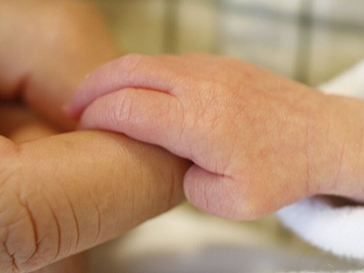 Close up of baby's hand holding the finger of a parent